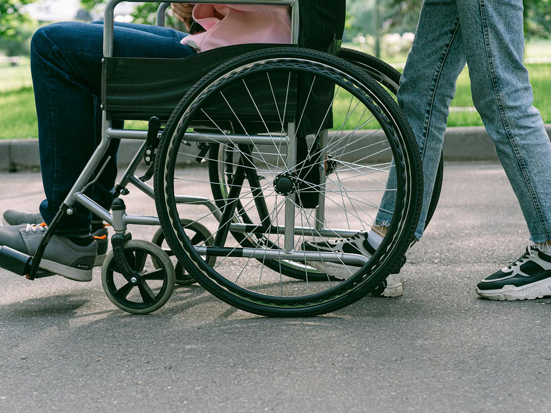 image de deux personnes se déplaçant vers la gauche, une en fauteuil roulant - Mathilde Freyssinet Éducatrice Spécialisée